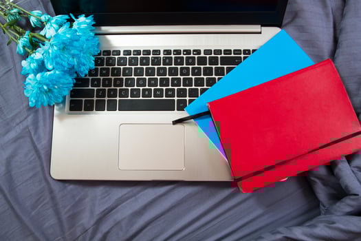 Laptop background on bed, notebooks and blue flowers, work space photo