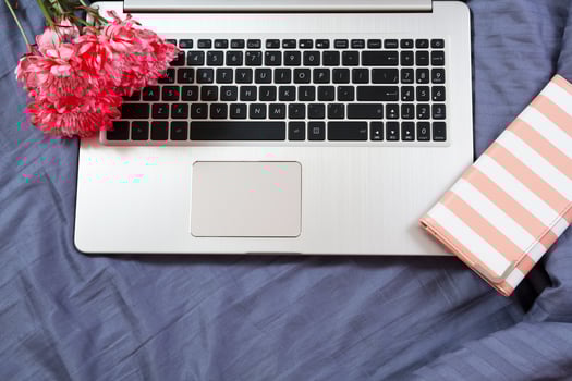 Work space at home, keyboard top view, female hand close up, notebook, work space on bed top view, flowers, colour background photo