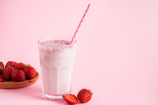 Fresh milkshake with strawberries on pink background. photo