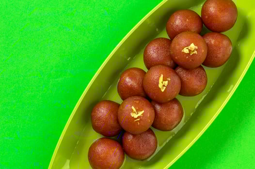 Gulab Jamun in plate on green background. Indian Dessert or Sweet Dish. photo