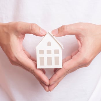Small white house on human hand photo