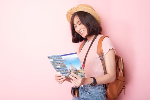 Happy Asian woman tourist  on pink background photo