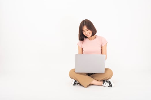 Cute Asian teen woman is working with computer on white background photo