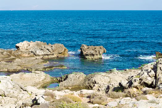 The waves breaking on a stony beach, forming a spray. Wave and splashes on beach. Waves crashing onto rocks. photo