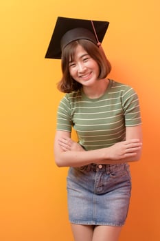 Portrait of young Asian student wearing graduation cap over studio background. photo