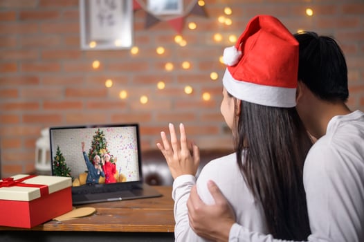 Young couple wearing red Santa Claus hat making video call on social network with family and friends on Christmas day. photo