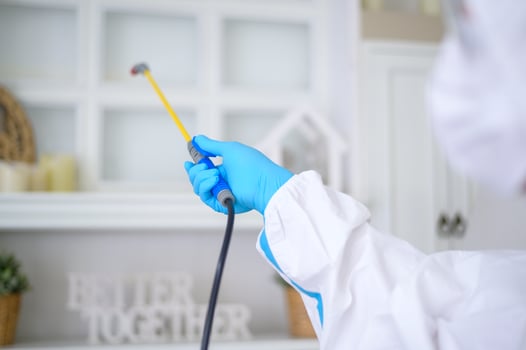 A medical staff in PPE suit is using disinfectant spray in living room, Covid-19 protection , disinfection concept . photo