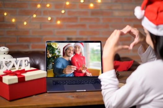Young smiling woman wearing red Santa Claus hat making video call on social network with family and friends on Christmas day. photo