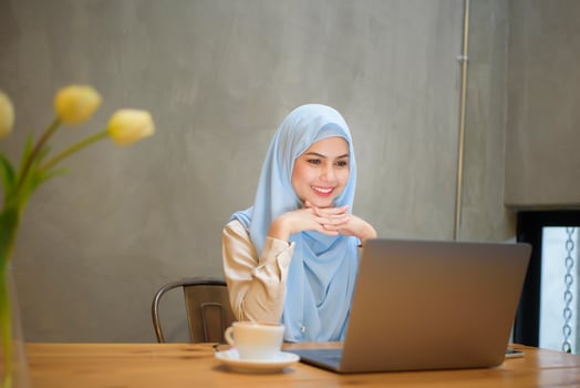 Muslim woman with hijab is working with laptop computer in coffee shop photo