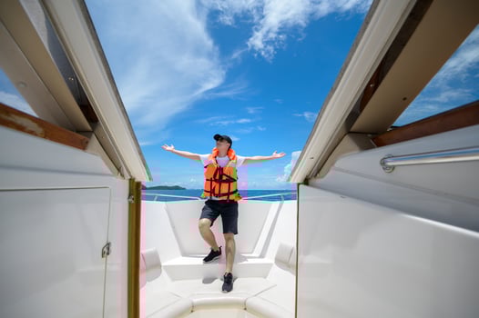 tourist in life jacket enjoying and relaxing on speedboat with a beautiful view of ocean and mountain in backgound photo