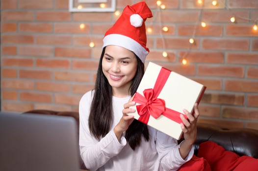 Young smiling woman wearing red Santa Claus hat making video call on social network with family and friends on Christmas day. photo