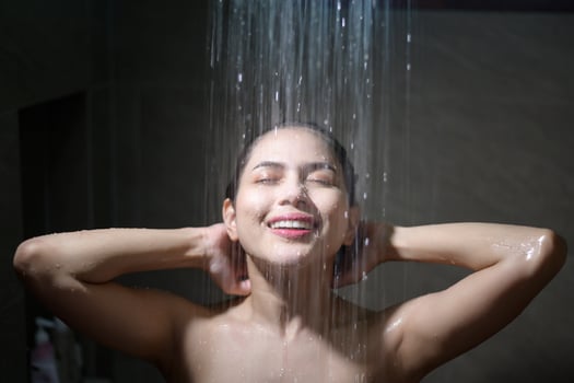 Young beautiful woman taking shower in a bathroom at home photo