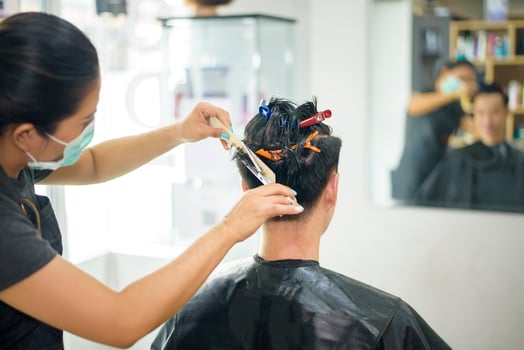 a young man is getting a haircut in a hair salon, Salon safety concept photo
