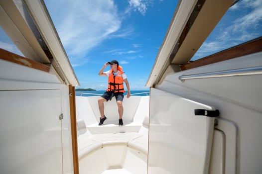 tourist in life jacket enjoying and relaxing on speedboat with a beautiful view of ocean and mountain in backgound photo