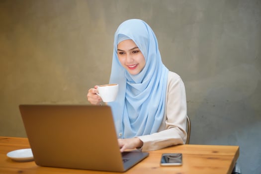 Muslim woman with hijab is working with laptop computer in coffee shop photo