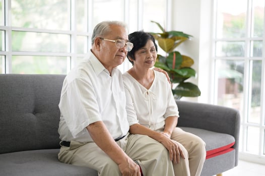 Elderly Asian couple watching television sitting on a sofa photo