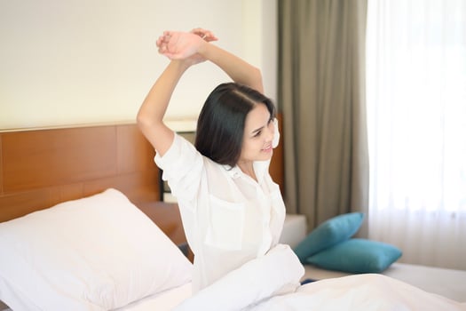 A smiling woman stretching her hands after waking up in the morning at home. photo