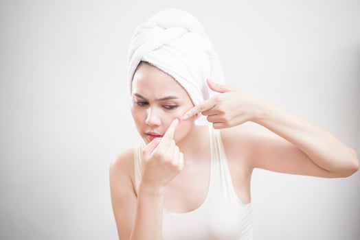 A woman is popping a pimple photo