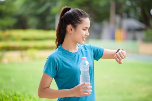 Happy young woman in sportswear using smart watch while exercising in park photo
