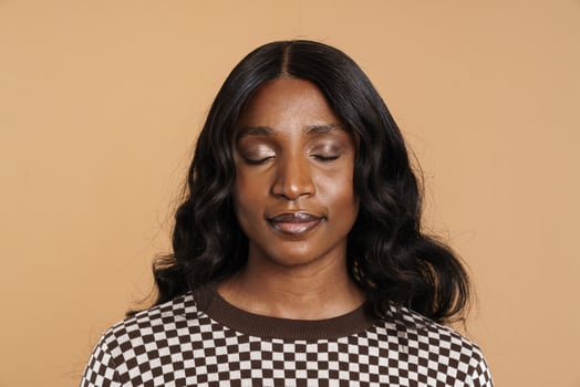 Calm positive African woman standing with closed eyes photo