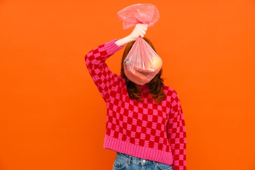 Young woman wearing plaid sweater holding plastic trash bag photo