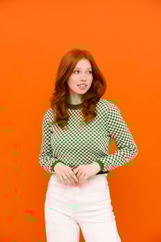 Young ginger-haired woman in plaid sweater smiling and looking aside photo
