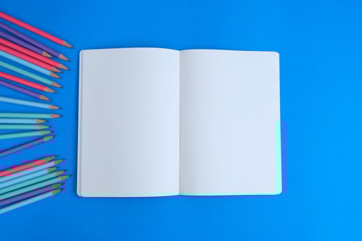 Blank notebook, a pencil, and space are on top of a blue office desk table. Flat lay, top view education concept photo