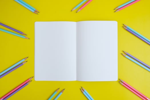 Blank notebook, a pencil, and space are on top of a yellow office desk table. Flat lay, top view education concept photo