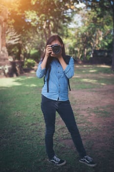 Young attractive woman photographer tourist with backpack coming to shoot photo at ancient phanom rung temple in thailand.