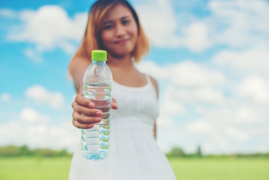 Women lifestyle concept young pretty  woman wearing white dress holding bottle of water at grassland smiley to camera look so fresh enjoy and happy. photo