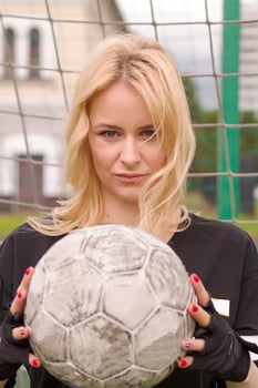 Beautiful blonde with a ball at the football goal. photo