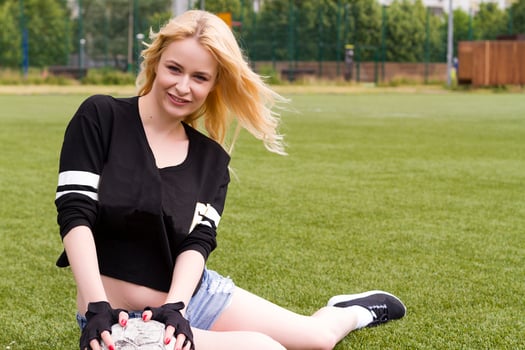The girl is sitting on the football field with the ball. photo