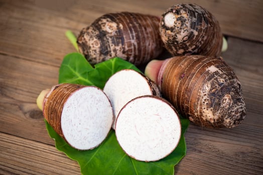 Fresh raw organic taro root ready to cook, Taro root with half slice on taro leaf and wooden background photo