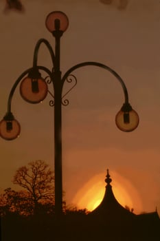 Silhouetted lamp post with glass bulbs at sunrise photo