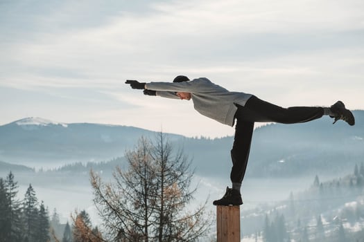 Man practicing yoga and balancing exercises in the winter mountains and enjoying life. Copy, empty space for text photo