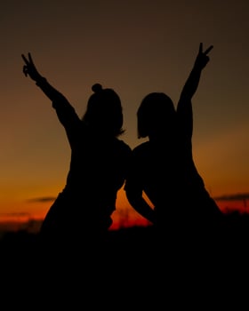 Silhouette of girls make heart with their hand. Happy friendship concept. photo