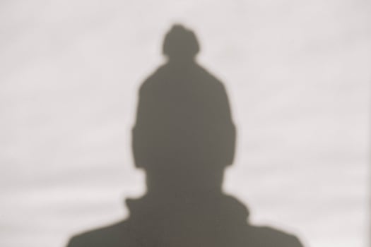 Shadow and silhouette of a man in a winter hat on a white wall photo