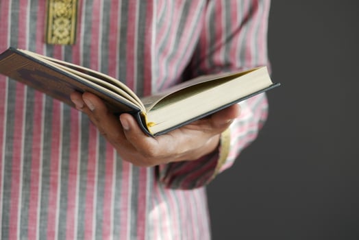 muslim man hand holding Holy book Quran with copy space photo