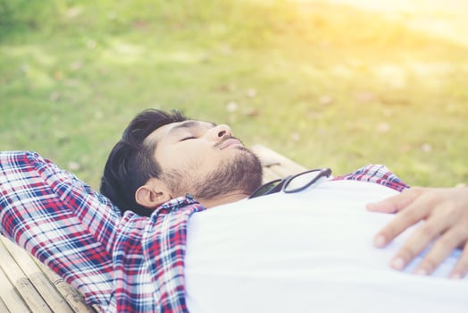 Happy young hipster lying on bench in the nature park. photo