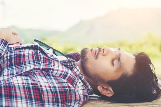 Happy young hipster lying on bench in the nature park. photo