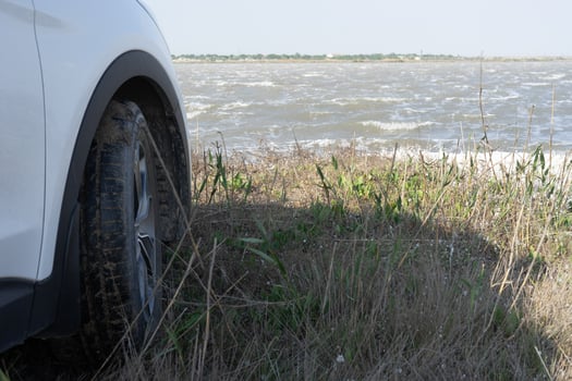 Natural landscape with a white car on the shore of a mud lake. photo