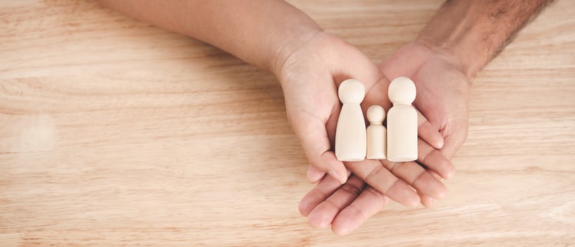 Man husband and Woman wife hands holding wooden peg dolls on the wood table background. family home, foster care, homeless charity support concept, family mental health. photo