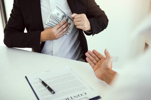 Businessman putting stack of money bills in his suit coat pocket. photo