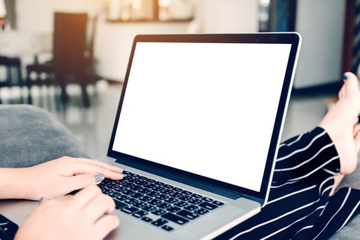 Woman sitting on chaise longue and using laptop blank screen at home. photo