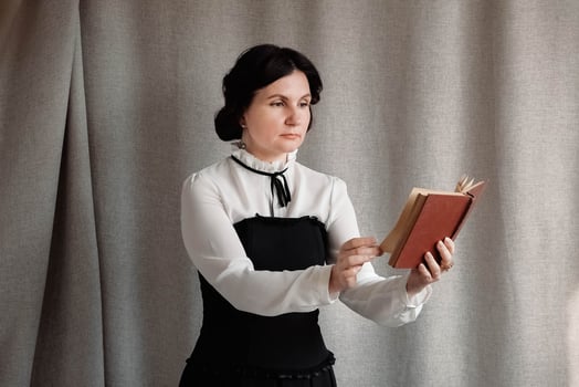Woman in vintage style dressed holding a book in his hands on a background of linen cloth photo