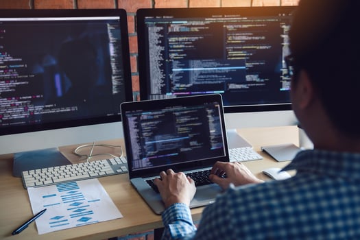 Rear view of software developers is sitting serious analyzing data on the computer screen. photo