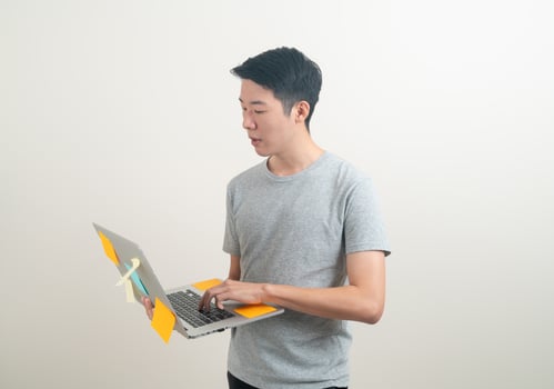 young Asian man holding laptop with stress face or working hard photo