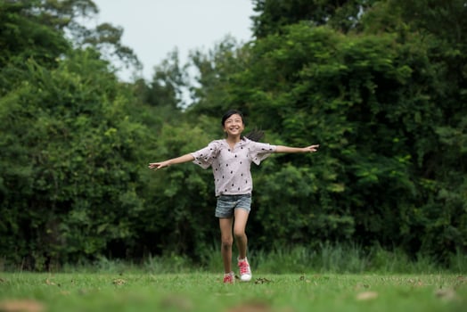 Happy cute little girl running on the grass in the park photo