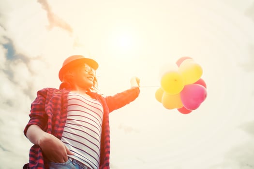 Young hipster woman holding balloons against sky photo