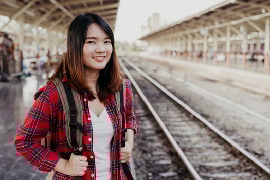Young Asian woman backpacker traveler walking alone at train station platform with backpack. Asian woman waiting train at train station for travel. Summer holiday traveling or young tourist concept. photo